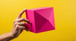 © wiplens - Hand Holding Pink Geometric Object Yellow Background