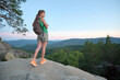 © bilanol - Sportive woman walking alone on hillside trail. Female hiker enjoying view of evening nature from rocky cliff on wilderness path. Active lifestyle concept