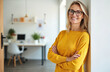 © miss irine - Middle-aged blond businesswoman smiles confidently at office. Happy female manager with crossed arms near wall in workplace. Successful, elegant, confident, professional adult woman with eyeglasses.