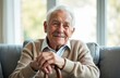 © miss irine - Happy, smiling elderly man rests on couch holding cane in living room. Headshot of a joyful senior with white hair, warm sweater, looking at camera. Portrait of content retirement, healthcare, life.