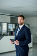© Halfpoint - Business professional standing with tablet in hand, ready for presentation
