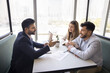 © fizkes - Stress free deal making. Positive male insurance agent real estate specialist win over multiethnic family couple of clients give professional advice in casual relaxed setting fostering trust comfort