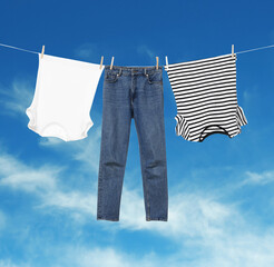 Wall Mural - different clothes drying on washing line against blue sky