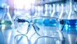 © Dreamera - Lentes de seguridad sobre superficie brillante junto a tubos de ensayo, imagen clara para ilustrar seguridad, investigación científica o procedimientos de laboratorio