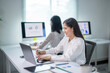 © Wasana - Two women are sitting at a desk with laptops and smiling