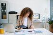 © laddawan - businesswoman reviewing analytics on tablet at bright office desk with charts, laptop, and documents. Concept of data planning