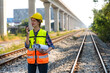 © Jack Tamrong - Female locomotive engineer with hand radio and blueprint working on the railway track