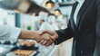 © mariyana_117 - Handshake between a chef and a business person in a commercial kitchen, representing partnership and collaboration in the food industry.