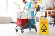© Pixel-Shot - Trolley with cleaning supplies and caution sign against janitors in office