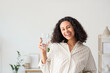© Pixel-Shot - Happy young African-American woman with glass of water at home
