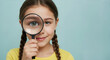 © Vasiliy - Smiling girl with braided hair holding magnifying glass over eye against light blue background. Scientific investigation and discovery for elementary education programs