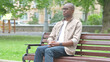 © stockbakers - Young African Man Coming to Sit on Park Bench