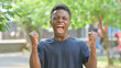 © stockbakers - Excited Casual African Man with Fists Pumped Outdoors