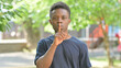 © stockbakers - Casual African Man Keeping a Secret Outdoors