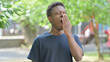 © stockbakers - Portrait of Tired Casual African Man Yawning Outdoors