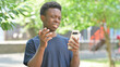 © stockbakers - Upset Casual African Man Reacting to Phone Content Outdoors