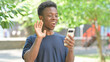 © stockbakers - Talking Casual African Man Doing a Video Call Outdoors