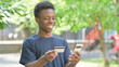 © stockbakers - Casual African Man Enjoying Online Shopping Outdoors