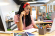 © WavebreakMediaMicro - African American woman typing on laptop at office desk wearing headset and reviewing printed charts