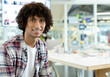 © WavebreakMediaMicro - African American man sitting at desk in open-plan office, viewing display screen and smiling