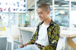 © WavebreakMediaMicro - Asian man sitting on white chair at light wood desk in open plan office using tablet