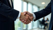 © Elena - Close-up of two men in business suits shaking hands in a spacious bright room