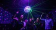 © photoplotnikov - Group of young adults dancing under disco ball with laser lights in nightclub