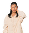 © Asier - Young Filipina woman touching back of head, thinking and making a choice.