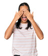© Asier - Young Filipina woman covers eyes with hands, smiles broadly waiting for a surprise.