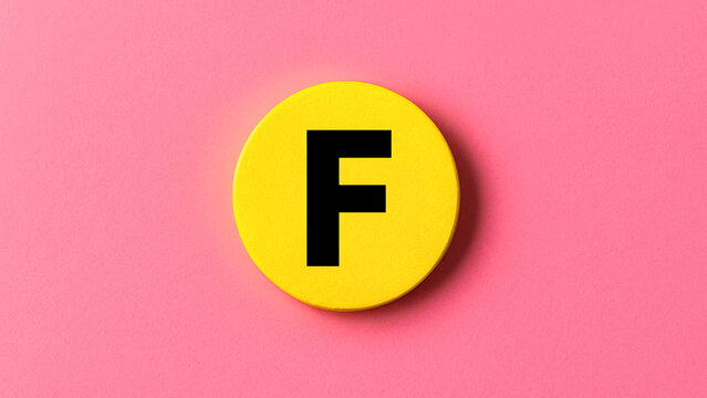 Bright yellow painted wood disk featuring bold letter F in the middle representing alphabet icon signage learning education monogram initial or creative typography lettermark for modern visuals

