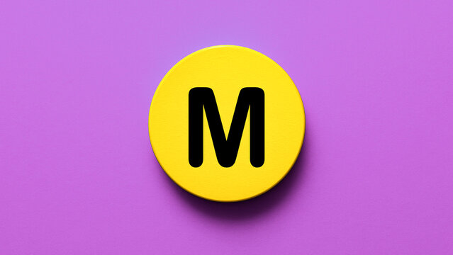 Wooden round badge coated yellow with large bold letter M ideal for alphabet symbol school learning monogram signage education icon or creative lettermark design on a clean background

