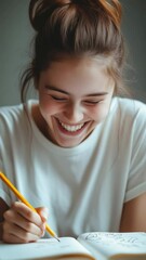 Poster - Young woman with her hair tied up, wearing a white t shirt, happily drawing in her notebook with a pencil while studying at home, radiating joy and creativity in her learning environment
