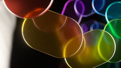Poster - Multiple colorful oval shapes, resembling pills or candies, glow and rotate against a black background, creating a visually appealing abstract animation