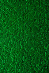  Textured green fabric with embossed swirling floral leaf pattern and dramatic lighting