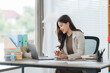 © Kritdanai - Focused Professional in Modern Office: A stylish businesswoman, illuminated by natural light, navigates her tasks with focused determination in a sleek, contemporary office setting.