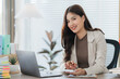 © Kritdanai - Businesswoman at Desk: A focused businesswoman at a well-lit office desk, skillfully working on a laptop. The environment radiates a professional ambiance.
