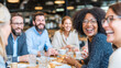 © Mikhail - Candid shot of a diverse group of friends (20s-30s) sharing a laugh over coffee and pastries at a stylish cafe.