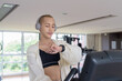 © Ranta Images - Non-binary gay man with mustache and androgynous appearance working out indoors in gym. Wearing feminine sports bra and using water bottle. Inclusive fitness concept with genderfluid representation.