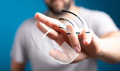 Poster - Stock photo of a person's hand interacting with a translucent phone icon and wifi signal, representing communication and technology.