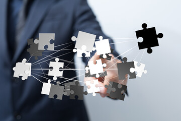 Poster - Image of a businessman connecting puzzle pieces, symbolizing teamwork, problem-solving, and strategic planning.