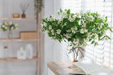 Bouquet of beautiful jasmine flowers in vase on wooden table indoors. Space for text