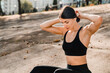 © InsideCreativeHouse - Confident Caucasian woman in athletic wear with earphones sitting relaxing outdoors, ready for a workout looking away on promo. Modern city lifestyle and fitness concept copy space.