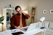 © djile - Man experiencing neck pain while working at desk