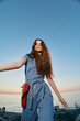 © SHOTPRIME STUDIO - Lifestyle woman in modern boho-western denim street style with long hair by the sea during golden hour, film color enhancing casual youthful vibe and relaxed pose.