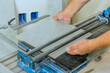 © ungvar - Skilled worker uses tile cutter to carefully slice a large ceramic tile at construction site.