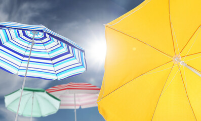 Wall Mural - different bright beach umbrellas against blue sky on sunny day