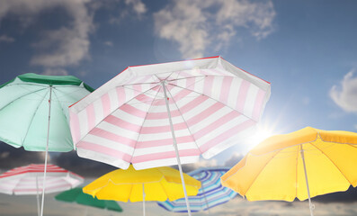 Wall Mural - different bright beach umbrellas against blue sky on sunny day