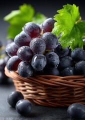 Poster - Fresh ripe dark purple grapes with water droplets in a wicker basket on dark surface with green leaves for healthy fresh fruit display