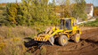 © Hanna - Yellow bulldozer at a construction site. Big wheel excavator leveling and clearing the land plot side view. Moving earthworks soil. Copy space. Building area. Special transport. High quality photo.