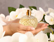 © Arda ALTAY - A woman's hands gently cradle a perfume bottle surrounded by white orchids, capturing elegance and luxury in a fragrant setting.